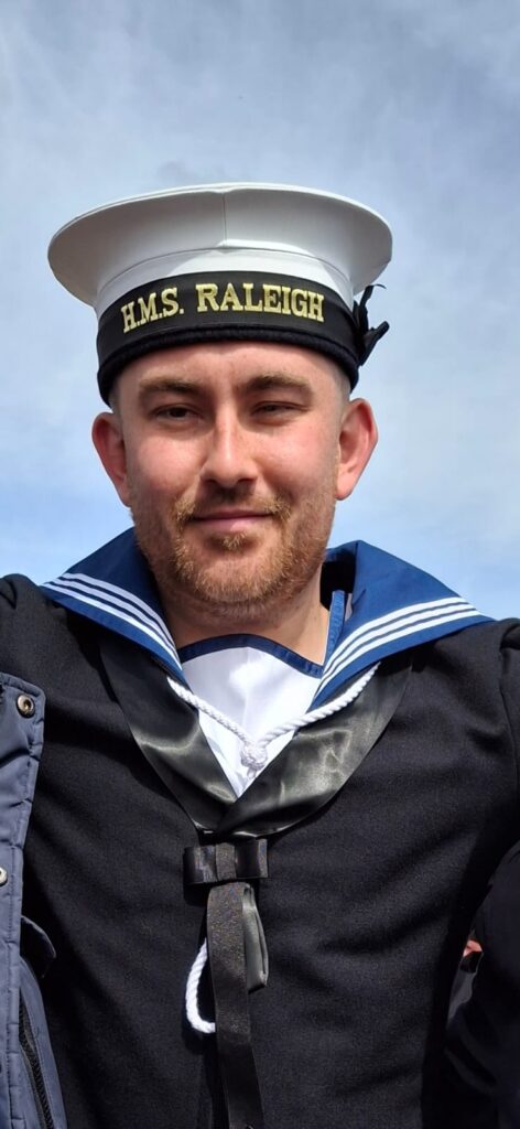 Joseph wearing a Royal Navy sailor's uniform and HMS Raleigh cap